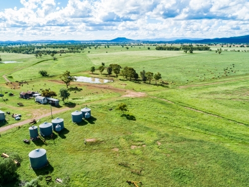 Silos and dam in green paddocks of grass on a farm - Australian Stock Image
