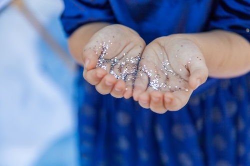 Silver glitter sparkles on childs hands
