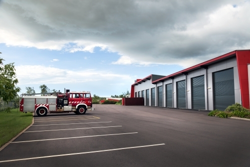 Single fire truck parked outside large modern shed - Australian Stock Image