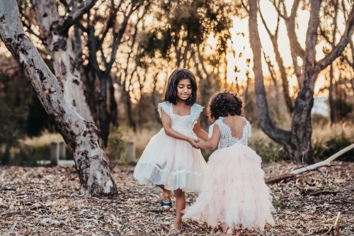 Sisters holding hands at the park, sisters dancing at the park, two girls at the park - Australian Stock Image