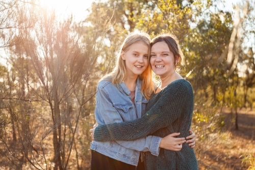 Sisters laughing together and giving one another a hug - Australian Stock Image