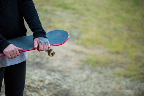 Skateboard being held with tattooed hands - Australian Stock Image
