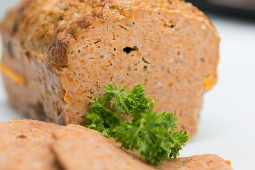 Sliced meatloaf in butchers shop with parsley garnish - Australian Stock Image