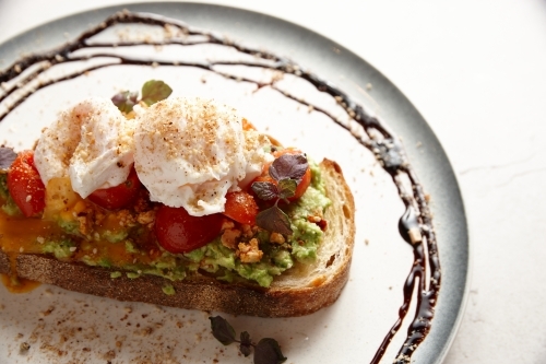 smashed avocado toast with tomato and poached eggs - Australian Stock Image