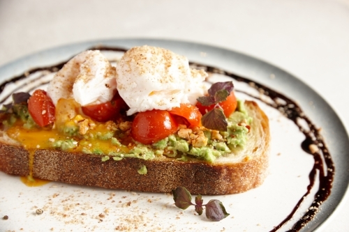 smashed avocado toast with tomato and poached eggs - Australian Stock Image