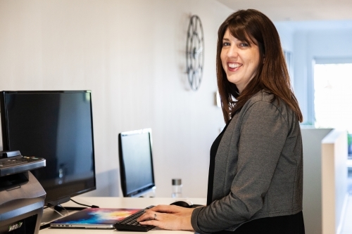 Smiling businesswoman standing at stand up desk in home office - Australian Stock Image