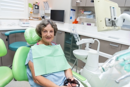 Smiling elderly female patient in dental chair - Australian Stock Image