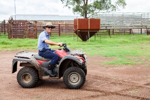 Smiling farmer on quad bike with hat and sunglasses - Australian Stock Image