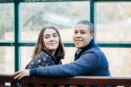 smiling lgbtqi couple sitting on a bench - Australian Stock Image