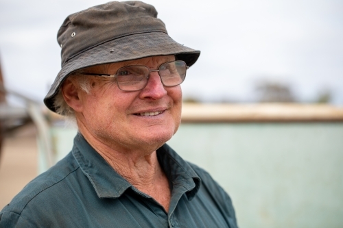 smiling older man wearing glasses and bucket hat - Australian Stock Image