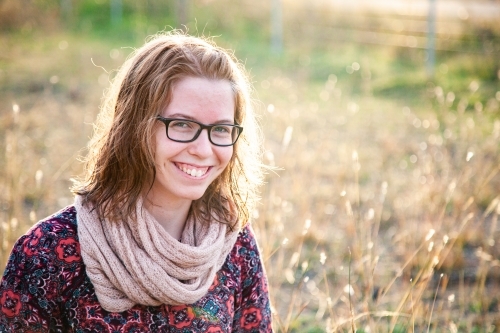 Smiling teenager with scarf outside in natural surroundings - Australian Stock Image