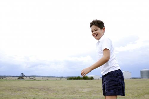 Smiling young boy in sport uniform standing in a farm paddock - Australian Stock Image