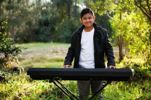 Smiling young person playing keyboard outside - Australian Stock Image