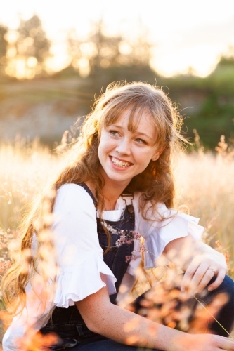 Smiling young woman outside in fluffy grass - Australian Stock Image