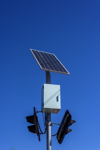 Solar panel powered traffic light against blue sky background, clean energy in use - Australian Stock Image