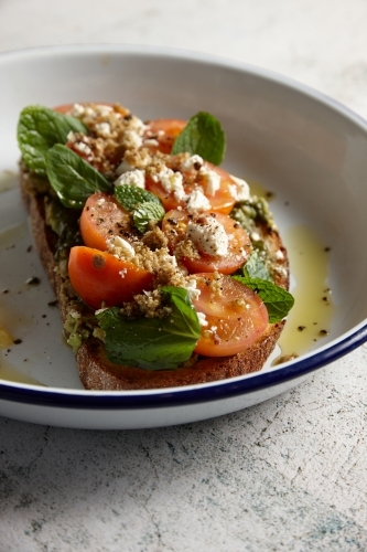 Sourdough with avocado, tomatoes, feta and herbs served with oil and lemon - Australian Stock Image
