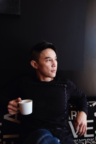 Southeast Asian multicultural man drinking coffee - Australian Stock Image