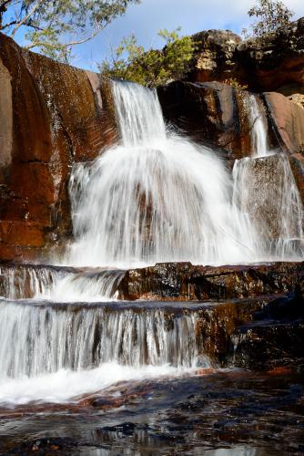 Spectacular tiered waterfall over colourful red sandstone - Australian Stock Image