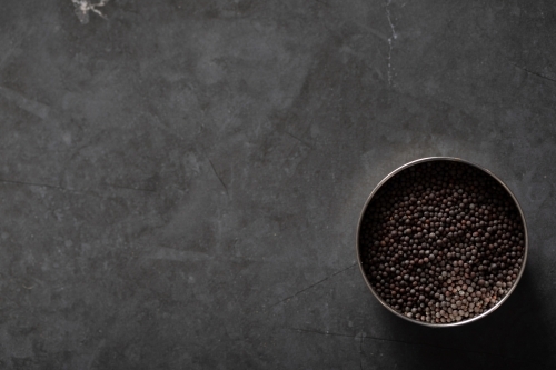 Spice tin of black mustard seeds on a dark marble background - Australian Stock Image