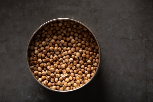 Spice tin of coriander seeds on dark marble background - Australian Stock Image