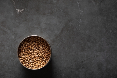 Spice tin of coriander seeds on dark marble background - Australian Stock Image