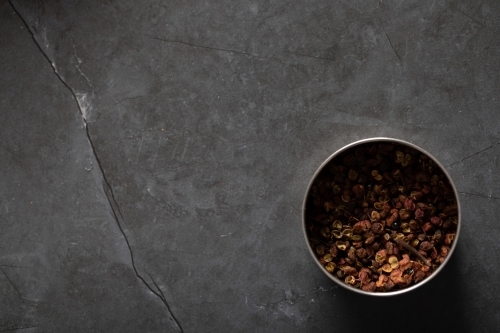 Spice tin of Sichuan pepper on dark marble background - Australian Stock Image