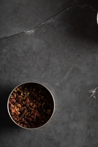 Spice tin of Sichuan pepper on dark marble background - Australian Stock Image