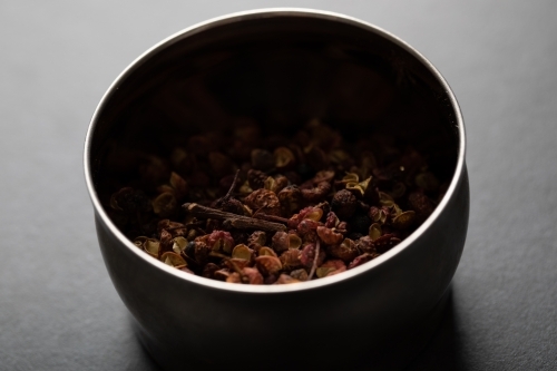 Spice tin of Sichuan pepper on dark marble background - Australian Stock Image