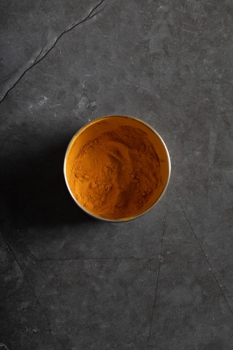 Spice tin of turmeric on dark marble table - Australian Stock Image