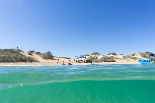 Split shot, half underwater shot, of family enjoying remote beach in Western Australia - Australian Stock Image