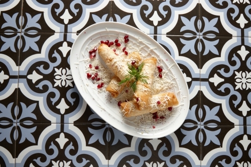 Spring rolls on plate on a tiled floor - Australian Stock Image