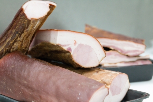 Stack of uncut bacon on trays in butcher shop - Australian Stock Image