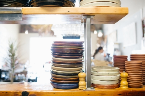 Stacks of plates and dishes on shelf in cafe - Australian Stock Image