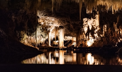 Stalactites and Stalagmites over a lake within a cave - Australian Stock Image