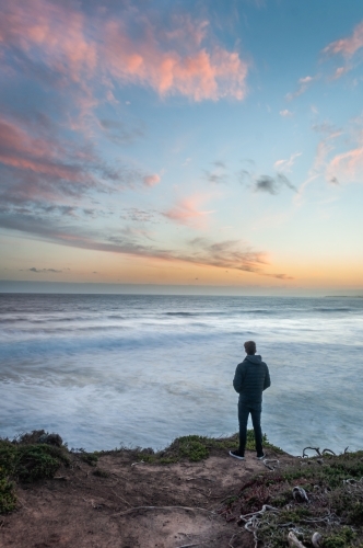 Man Standing on a Great Ocean Road Cliff at Sunset - Australian Stock Image