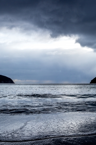 Storm clouds darken the sky over a beach - Australian Stock Image