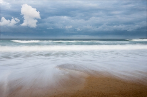 Storm clouds over beach with blurred wave action - Australian Stock Image