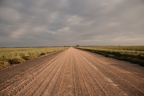 Straight gravel country road through emptiness of flat farmland - Australian Stock Image