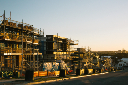 Suburban construction site with machinery and scaffolding, in evening sun - Australian Stock Image