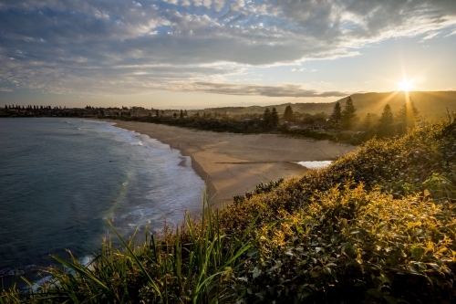 Sun setting behind empty beach - Australian Stock Image