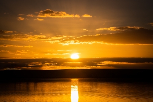 Sun setting over salt lake with reflections on the water - Australian Stock Image