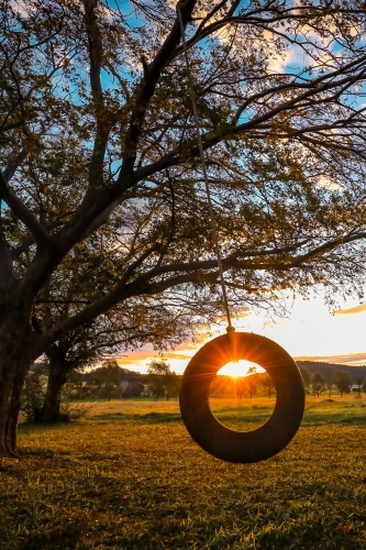 Sun setting through backyard tire swing on country property - Australian Stock Image