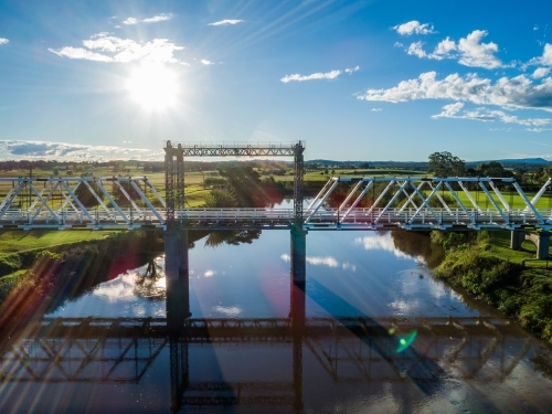 Sunlight over Paterson River with historical timber truss bridge - Australian Stock Image