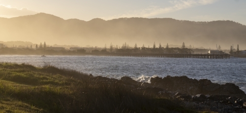 Sunrise coast view with sea mist and mountains in background - Australian Stock Image