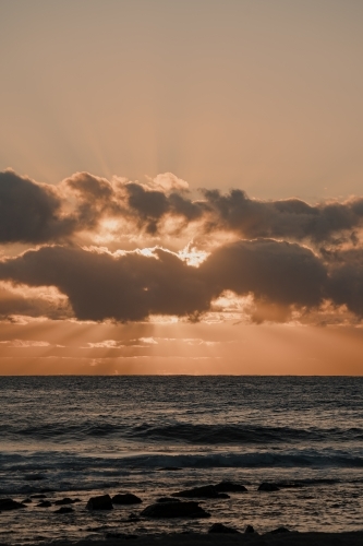 Sunrise through the clouds over the ocean at Bronte Beach - Australian Stock Image