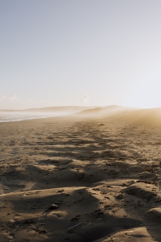 Sunset through sea mist over long empty Beach - Australian Stock Image