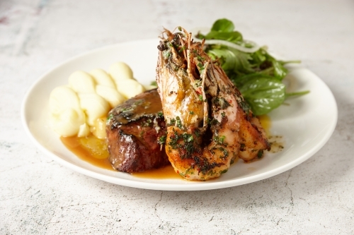 Surf and Turf - a steak and grilled prawns served with salad and mash - Australian Stock Image