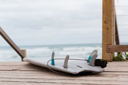 Surf board on wooden steps near beach - Australian Stock Image