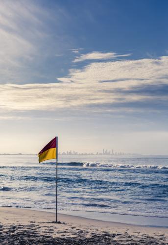 Surf Life Saving flag on beach with city in background - Australian Stock Image