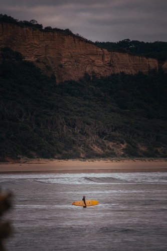 Surfer Standing on a Sand Bank in front of a Great Ocean Road Cliff - Australian Stock Image